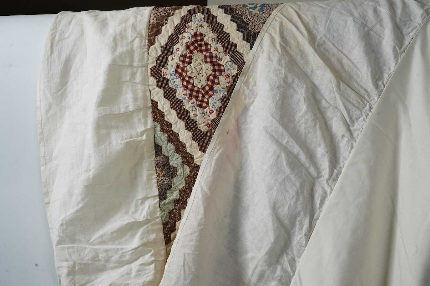 An ornate 19th century Log Cabin patchwork, made mostly from printed dress cottons from 1850-1900. 195cm long x 157cm wide., Condition - The colours are still bright and cotton strong. The patchwork backing and the cream